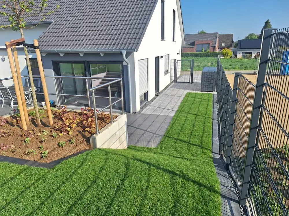 Neu angelegter Garten mit Rasen, Pflasterweg und Staudenbeet an einem Einfamilienhaus